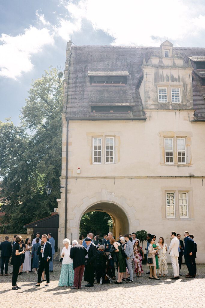 Hochzeitsgäste gratulieren dem Brautpaar beim Empfang auf der Schlossterrasse in Aerzen.