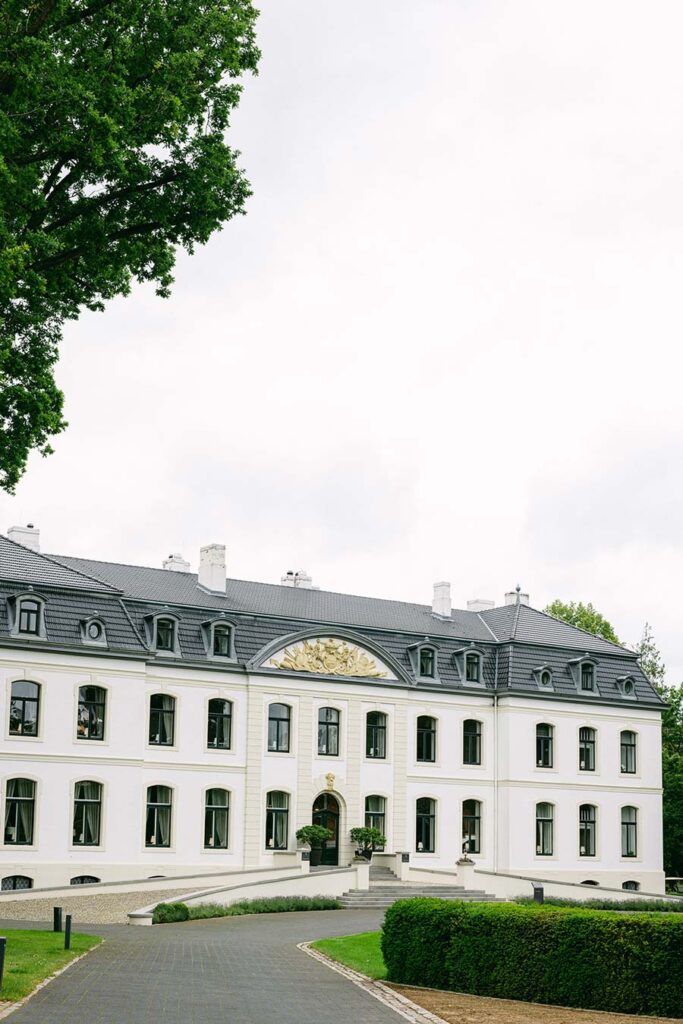 Außenansicht des imposanten Haupthauses von Schloss Weissenhaus bei Tageslicht, umgeben von gepflegten Parkanlagen.